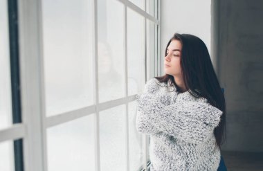 Genç kız nefis kahve tabakları içiyor ve günün planlarını düşünüyor.