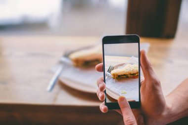 akıllı telefonlu bir sandviçin fotoğrafını çekmek.