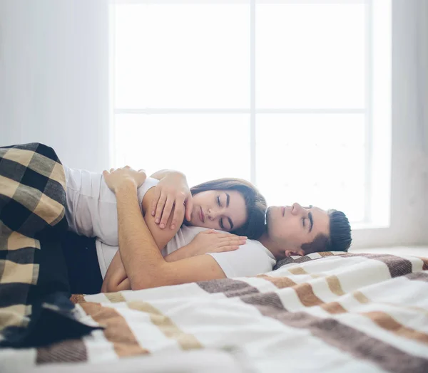 Milující pár leží na posteli. Jasná a útulná ložnice. Rodinný komfort a láska — Stock fotografie
