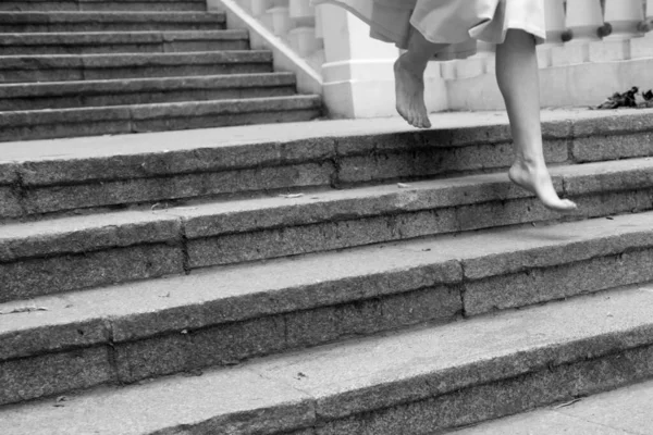 Pictre de mulher caucasiana descalça andando em degraus sozinha. Usa um vestido comprido. Vista de corte de imagem em preto e branco. Foto feminina . — Fotografia de Stock