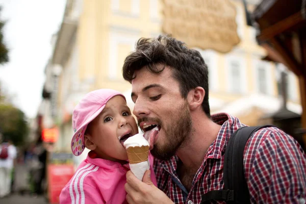 Picture of father liking white ice cream with daughter. Walking on sreet and have fun together. Tasty sweet ice cream. Spend time together. — Stock Photo, Image