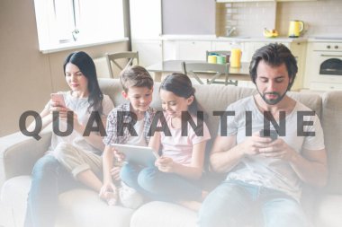 Ebeveynler çocuklarla kanepede oturuyor ve telefonlara bakıyorlar. Çocuklar erkek ve kadın arasındaki bahislerdedir. Kız tableti elinde tutuyor. Ekrana bakıyorlar..