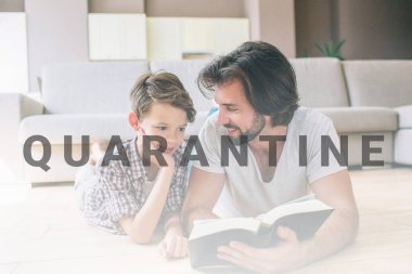 Çocuklar yerde yatıyorlar. Adam kitabı tutuyor ve oğluna bakıyor. Ona gülümsüyor. Çocuk utangaç. Elini yüzüne koydu..