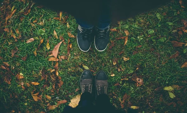 Homem e mulher estão em frente um do outro. Close up de pés em botas de inverno no gramado de outono — Fotografia de Stock