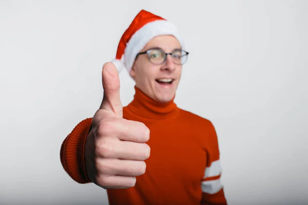 Щасливий красивий чоловік у різдвяному капелюсі показує великі пальці вгору — стокове фото