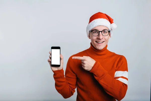Gelukkig knappe man in kerst hoed tonen smart phone mobiele telefoon — Stockfoto