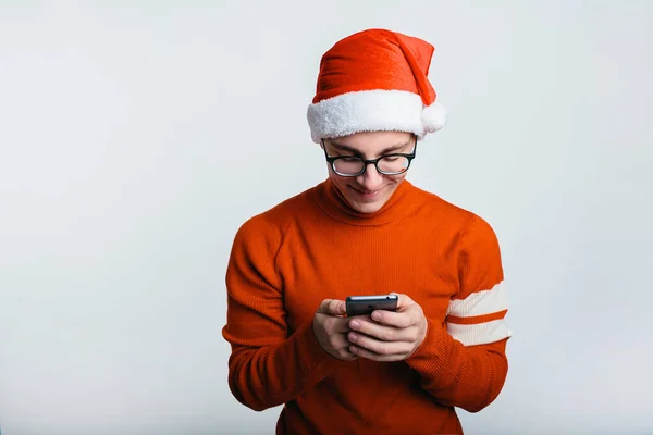 Gelukkig knappe man in kerst hoed gebruik maken van zijn smartphone — Stockfoto