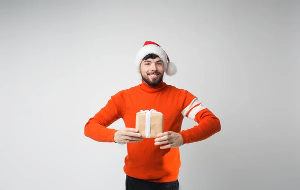 Jeune homme barbu isolé sur fond. gai heureux gars positif tenir présent dans les mains et poser sur la caméra. Célébration de Noël ou Nouvel An . — Photo