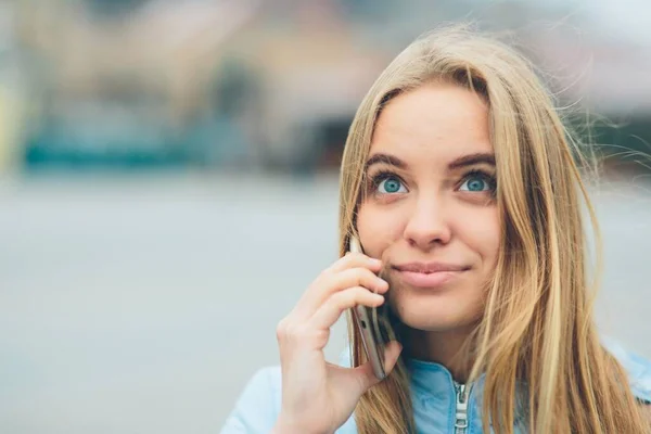 Эмоциональная красивая блондинка разговаривает по телефону на улице. Женщины коррумпированные лица и балуется в чате с друзьями по камере . — стоковое фото
