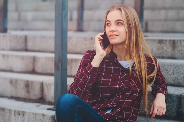 Het meisje zit op de trap en praat aan de telefoon. — Stockfoto