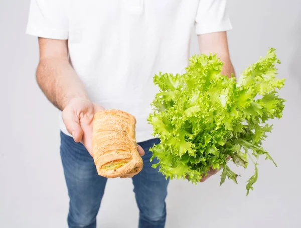 Homem segurando saladas e um pão de fechar. Isolado sobre um fundo branco . — Fotografia de Stock