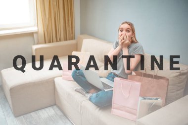 Evde online alışveriş. Genç, şaşkın bir kadın, alışveriş torbalarıyla kanepede otururken çevrimiçi dükkanda büyük indirim görüyor.