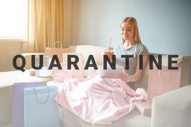 Evde online alışveriş. Çaylı genç sarışın kadın tablete bakıyor ve kanepede battaniyeyle otururken online dükkandan mal seçiyor.