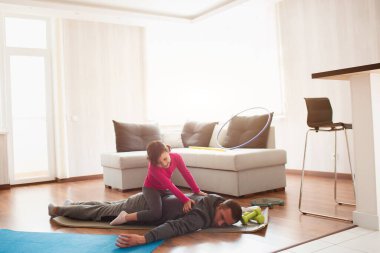 Baba ve kızı evde antrenman yapıyorlar. Apartman dairesinde egzersiz. Evde spor haberleri. Babam çok yorgun. Kızı sırtına bindi ve eğlendi..