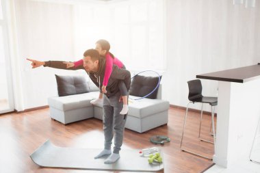 Baba ve kızı evde antrenman yapıyorlar. Apartman dairesinde egzersiz. Evde spor haberleri. Kızı sırtına bindi ve eğlendi..