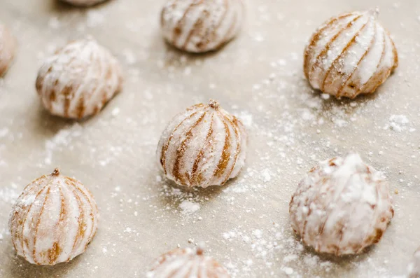 Små kakor täckt med vit choklad och pudrade socker bakplåtspapper — Stockfoto