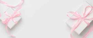 Beyaz arka planda pembe kurdeleli beyaz kutular. Üst görünüm, kopyalama alanı, afiş