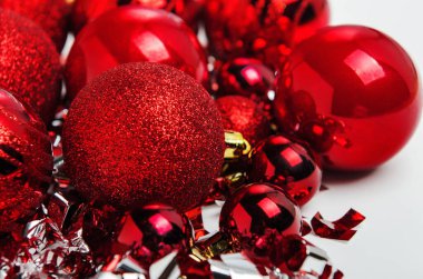 Beyaz arka planda parıltılı, konfeti ve flamalı parlak kırmızı noel topları. Yeni yıl, Noel geçmişi.