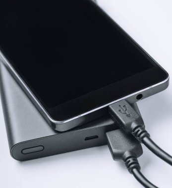 Beyaz arka plan üzerinde güç bankadan şarj siyah telefon smartphone. Modern teknoloji kavramı