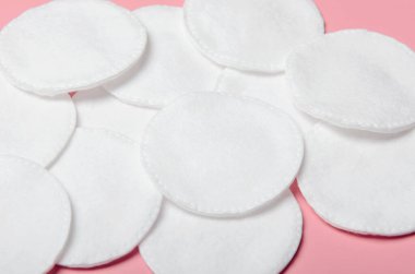 Pembe arka planda kişisel bakım için bir yığın pamuk. Makyaj malzemelerini çıkarırken dikkatli ol. Güzellik ve sağlık.