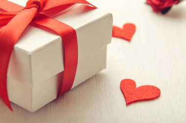 Keçeli kalple beyaz arka planda kırmızı fiyonklu beyaz hediye kutusu. Sevgililer Günü 'nde tebrik ederim, Kadınlar Günü.