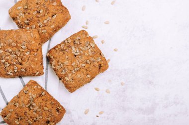 Arkaplanda havlunun üzerinde ayçiçeği tohumları olan ekmek. Sağlıklı yemek, vejetaryen. Boşluğu kopyala, üst görünüm, düz uzanma
