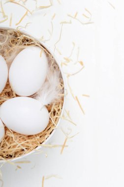 Yuvarlak bir kutuda yumurta ve beyaz bir arka plan. Paskalya kompozisyonu, bahar tatili, sağlıklı yiyecekler. Boşluğu kopyala, üst görünüm, düz uzanma