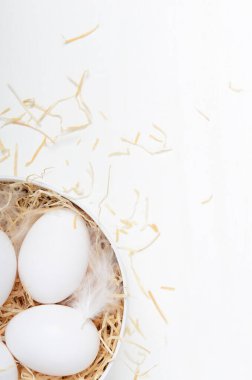 Yuvarlak bir kutuda yumurta ve beyaz bir arka plan. Paskalya kompozisyonu, bahar tatili, sağlıklı yiyecekler. Boşluğu kopyala, üst görünüm, düz uzanma
