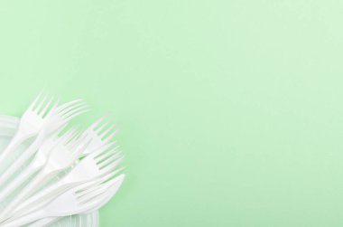 Yeşil arka planda plastik çatallar. Konsept yemekler, plastik kirliliği. Boşluğu kopyala, üst görünüm, düz uzanma.