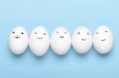 Kawaii mavi arka planda beyaz yumurtalara bakıyor. Çizgi filmler, çocuklar için dekorasyon yemekleri. Üst manzara, düz uzanma