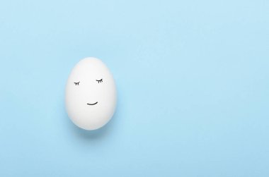 Kawaii mavi arka planda beyaz yumurtalara bakıyor. Çizgi filmler, çocuklar için dekorasyon yemekleri. Üst manzara, düz uzanma