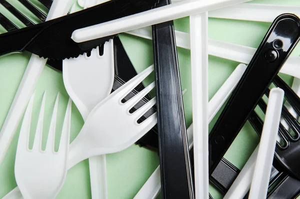 塑料白色和黑色叉子和刀绿色背景 概念塑料盘子 塑料污染 顶视图 — 图库照片