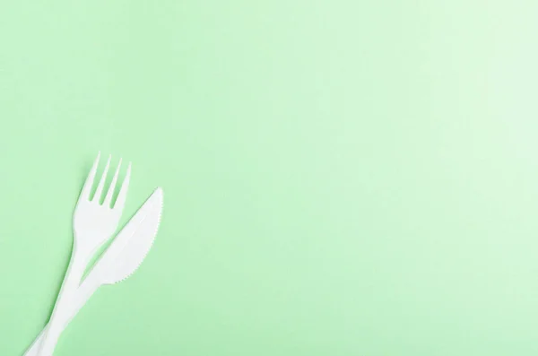 绿色背景上的塑料叉子和刀 概念塑料盘子 塑料污染 复制空间 顶视图 平面布局 — 图库照片