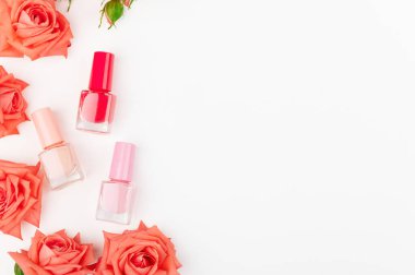 Beyaz arka planda izole edilmiş renkli ojeli cam şişeler. Pembe, kırmızı ve bej renkler. Çiçek süslemesi. Sağ tarafta uzayı kopyala. Salon prosedürü. Manikür-pedikür. Güzellik konsepti.