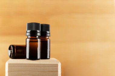 Aromaterapi, masaj yağı ya da temel kozmetik ürünleri için hazırlanmış cam şişeler. Ahşap tezgahtaki markasız bardaklar bej arka planda izole edilmiş. Sağ tarafta uzayı kopyala. Organik kozmetoloji kavramı.