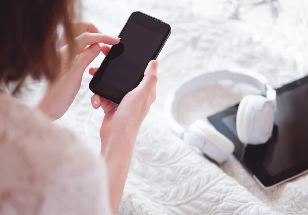 Top view of female hands holding smartphone. Woman surfing internet, social networks or chatting with friends. Copy space on cellphone display. Leisure time with gadgets at home.