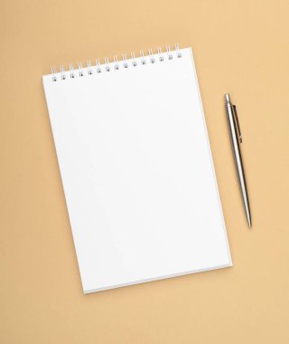 Kahverengi arka planda çelik kalemli beyaz defter. Ofis, yer ayır, maket yap, şablon yap, üst görünüm, düz yat