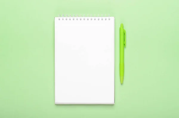白色笔记本 绿色背景上有明亮的霓虹灯绿色钢笔 复制空间 顶视图 平面布局 — 图库照片