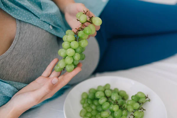 Mujer embarazada comiendo uvas — Foto de Stock