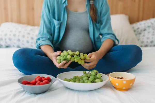 Mujer embarazada comiendo uvas — Foto de Stock