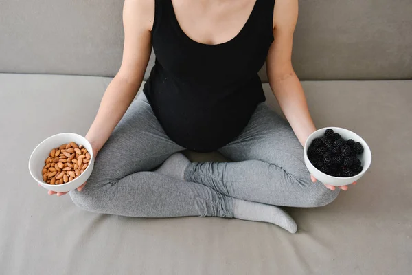 Mujer embarazada comiendo nueces y moras — Foto de Stock