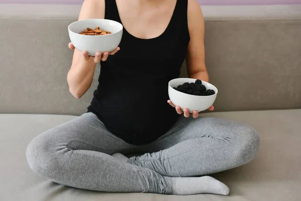 Mujer embarazada comiendo nueces y moras — Foto de Stock