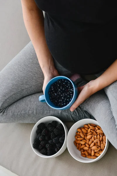 Mujer embarazada comiendo nueces y moras — Foto de Stock