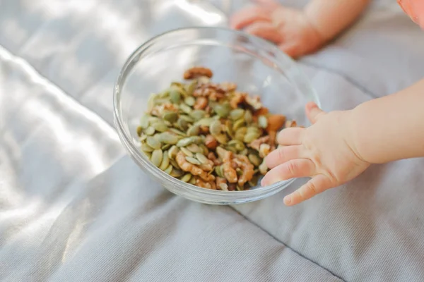 Детские руки и миска с семенами и орехами — стоковое фото