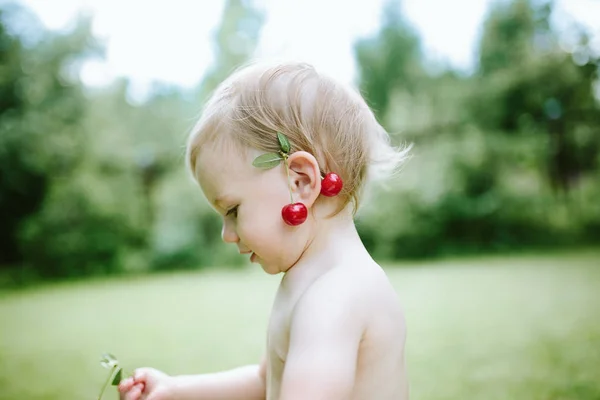 Niña con cerezas en la oreja —  Fotos de Stock