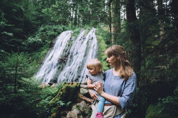 Мать с дочерью возле водопада в лесу — стоковое фото