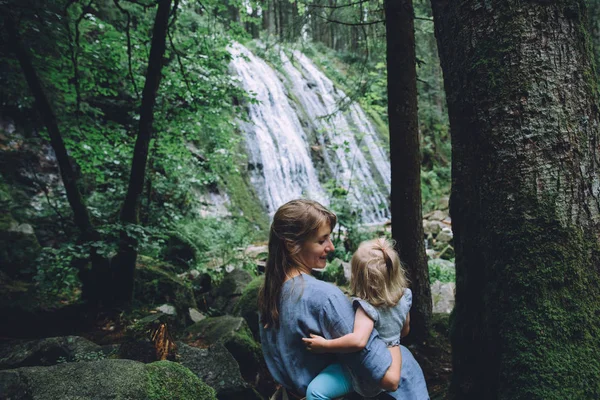 Moeder met dochter in de buurt van de waterval in bos — Stockfoto