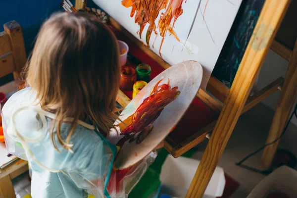 little girl drawing with paints and palette