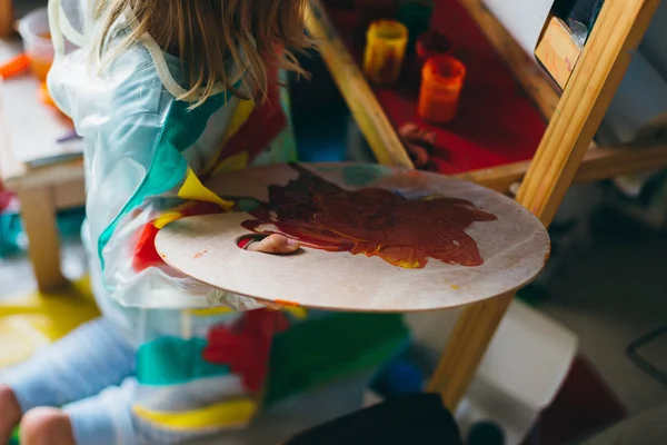 little girl drawing with paints and palette
