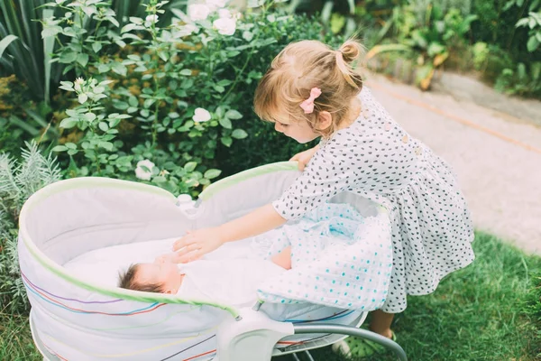 Meisje kijkend naar baby in kinderwagen — Stockfoto